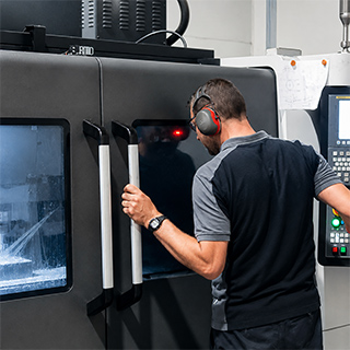 Operario trabajando con máquina CNC Operario trabajando en una máquina CNC en Loiolan